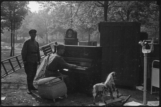 Советский солдат играет на пианино в пригороде Берлина в мае 1945 года. 